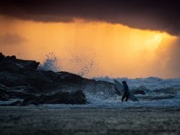 Person carrying surfboard in sea at newquay.