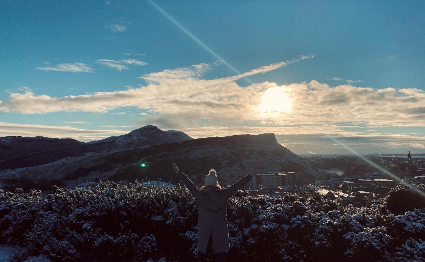 Woman standing on hilltop in edinburgh.