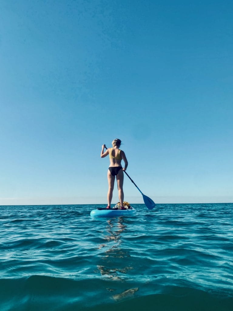 Woman paddleboarding in the sea at brighton beach.