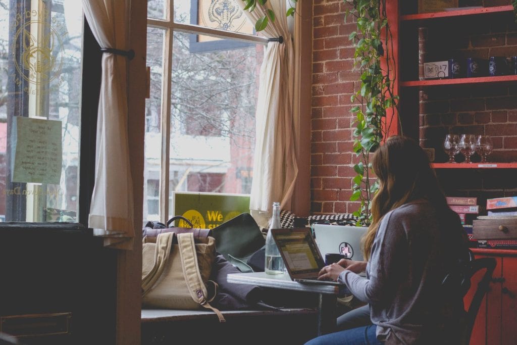 Woman works on laptop in cafe.