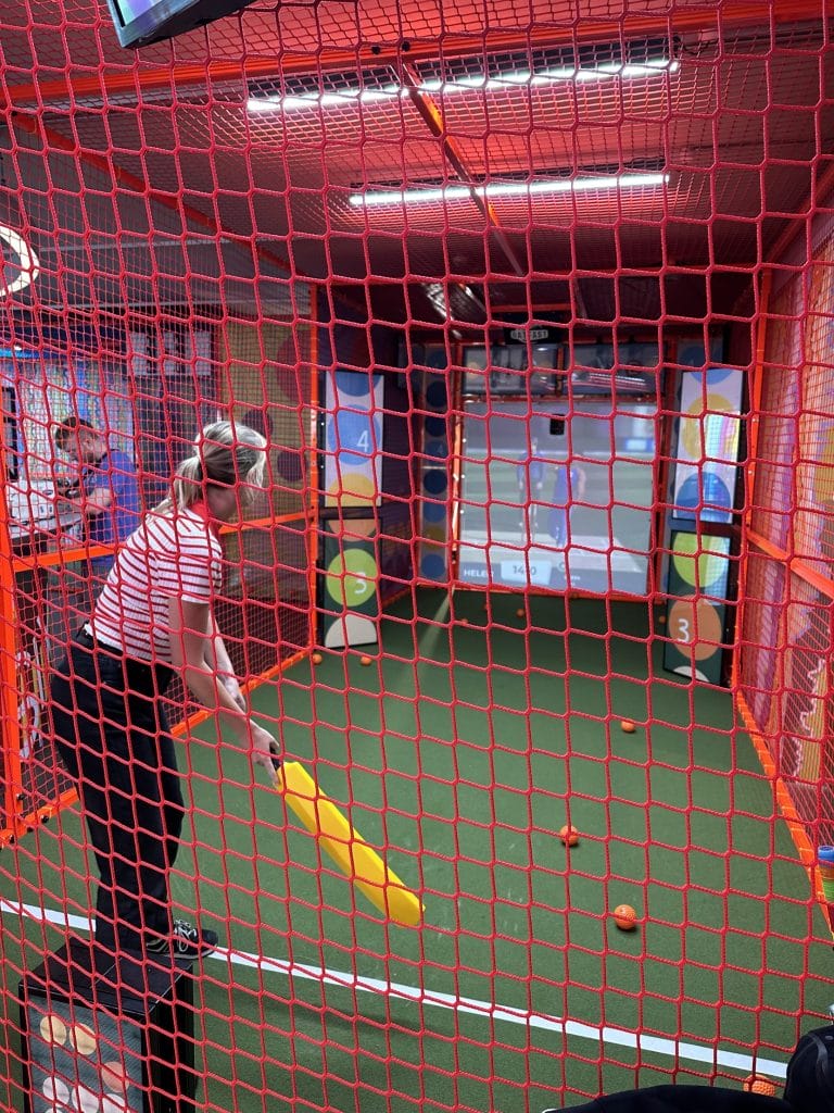 Woman in batting cage at sixes social cricket brighton.