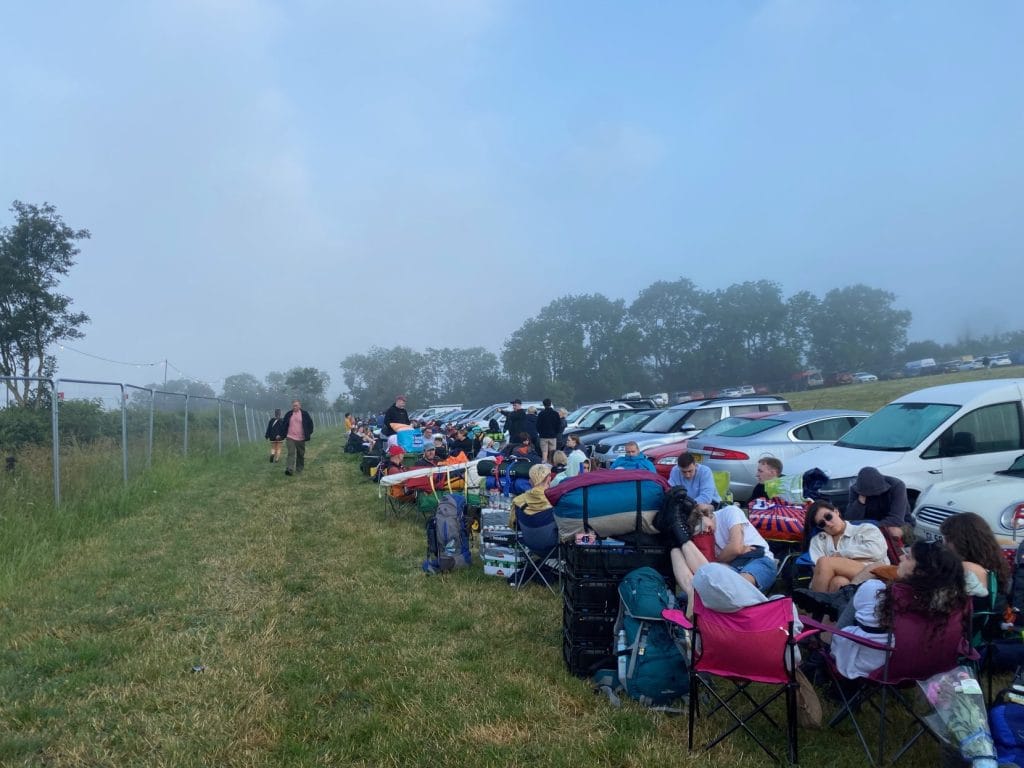 People sitting in queue in car park.