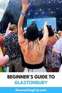 Woman holding up hands and dancing in front of Pyramid stage at Glastonbury Festival.